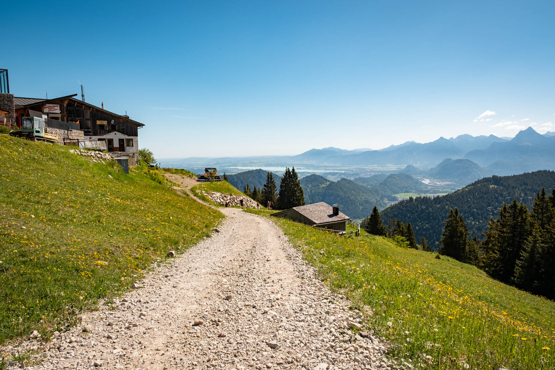 Breiter Schotterweg im Abstieg vom Breitenberg mit Bergen im Hintergrund