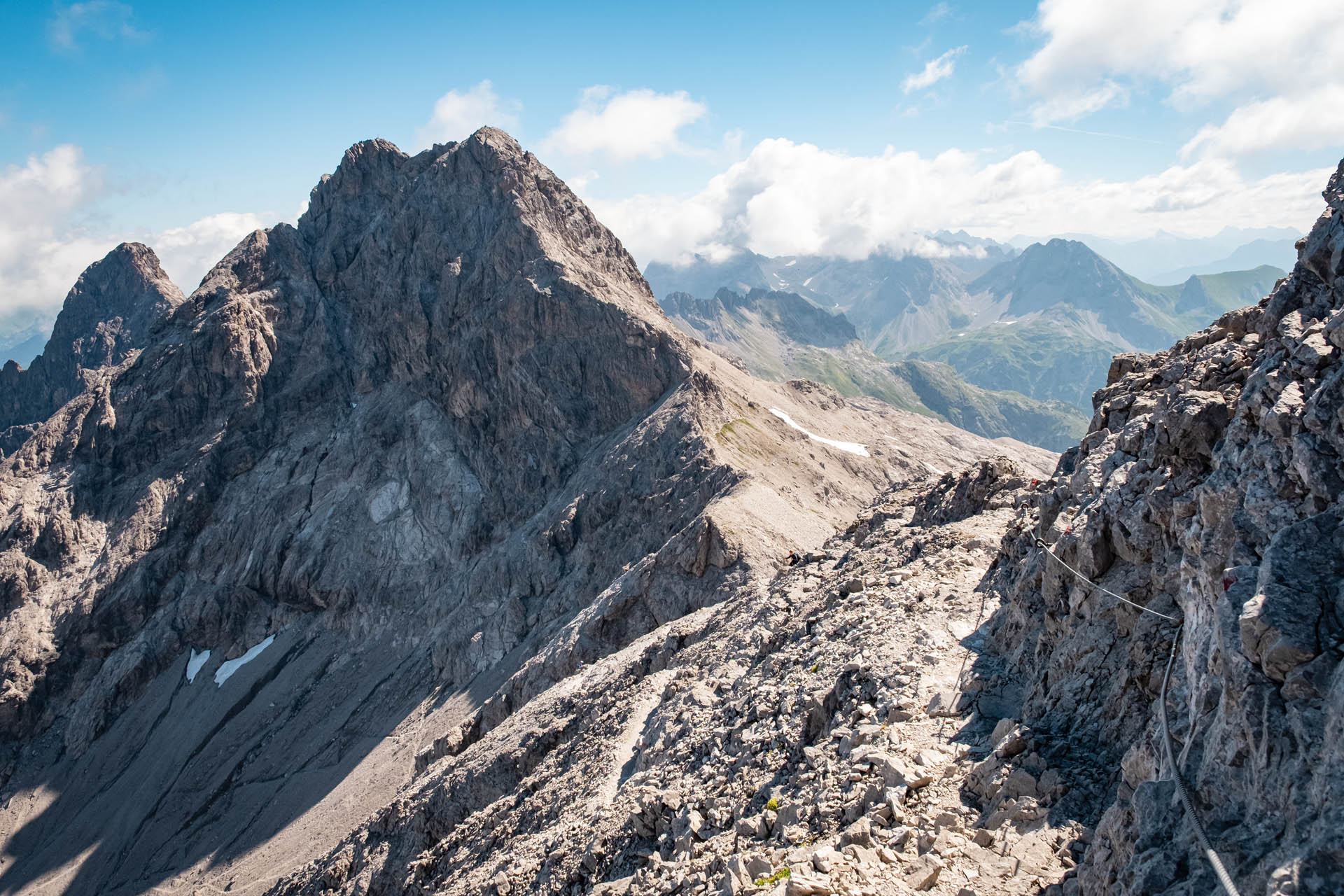 Abstieg vom Bockkarkopf über Fels und Geröll. Im Hintergrund das Allgäuer Dreigestirn mit Hochfrottspitze und Trettachspitze