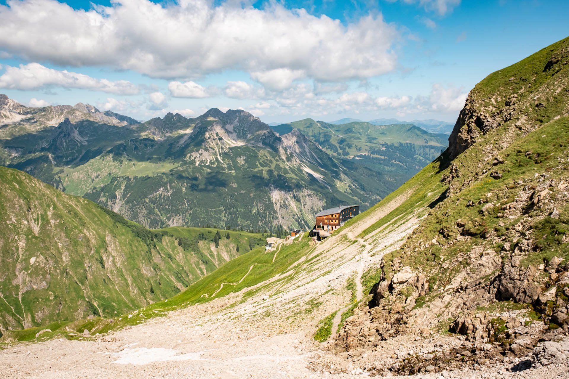 Das Waltenberger Haus, umgeben von den Bergen der Allgäuer Alpen und Schotter, sowie Wiesen
